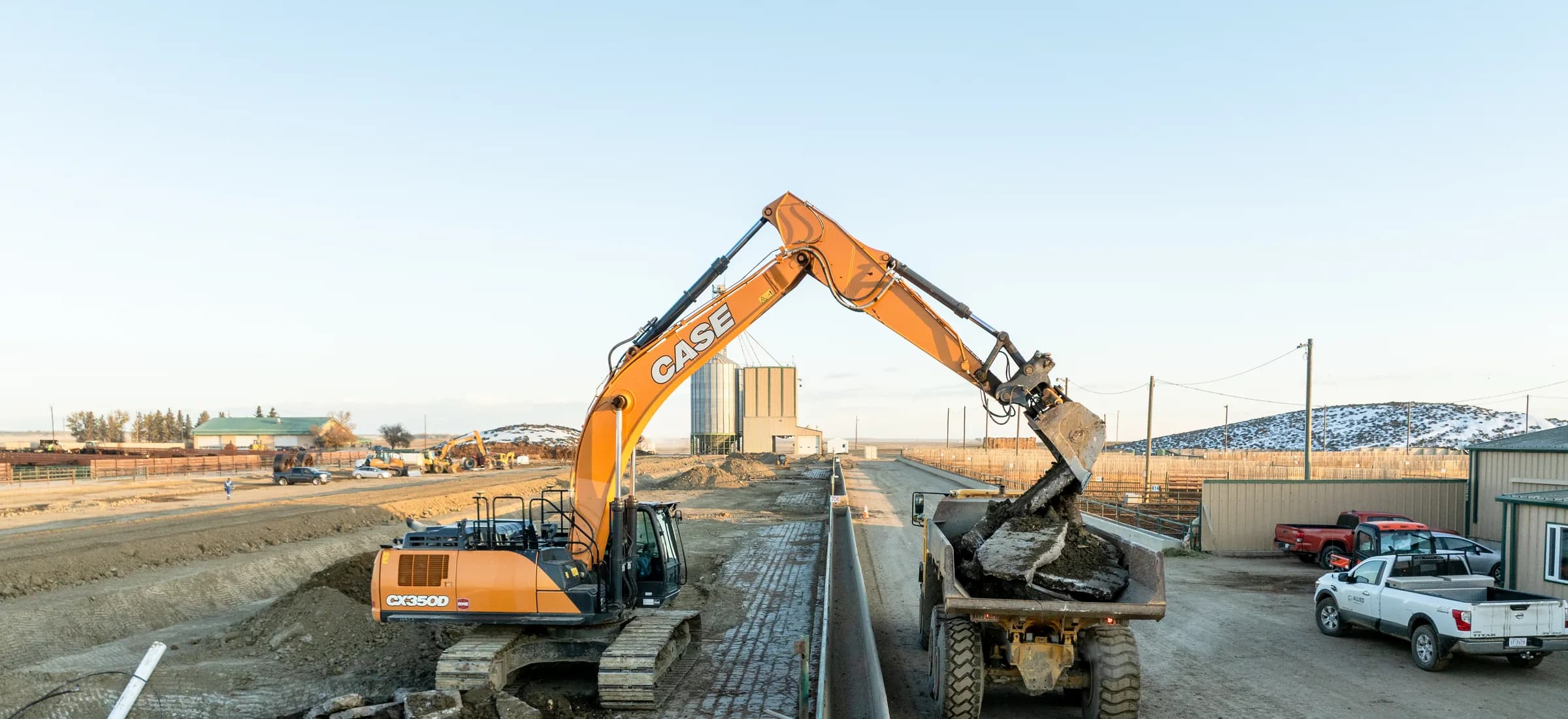 Subterrain demolition excavator loading broken concrete into an articulated dump truck at an Alberta worksite